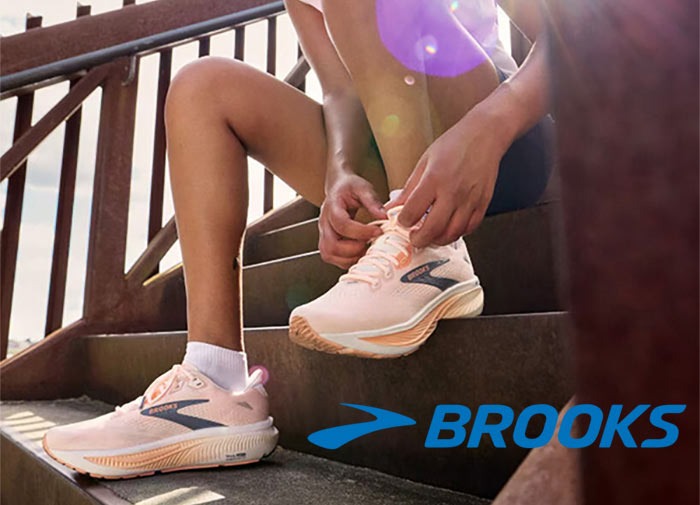 Person tying their Brooks shoes with logo overlay