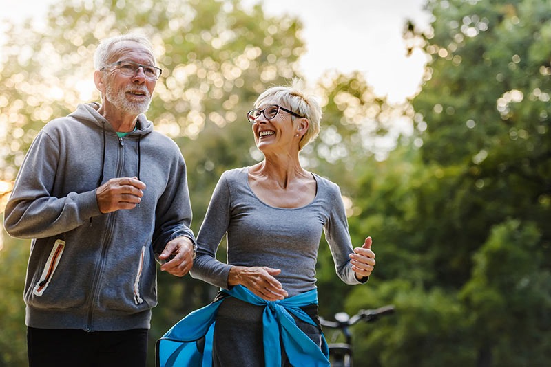 Older couple walking in an outdoor setting and smiling