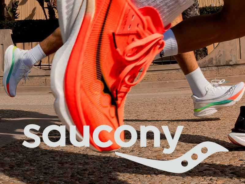 Action closeup of bright orange Saucony shoe in middle of running motion