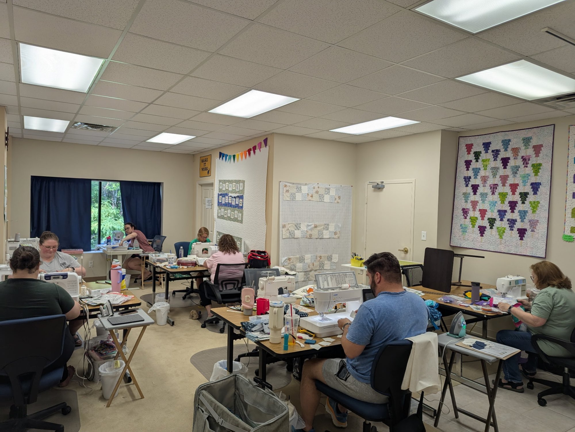 Students sit at sewing tables with sewing machine