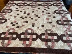 irish chain quilt with creams, browns and 2 inch colored squares inside the irish chain.