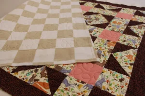 flannel baby quilt with peach, tans florals, amd brown borders with a checker board minky backing.