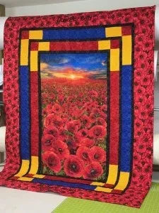 red poppie quilt with blue, yellow and black lettering on the quilt.
