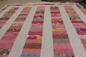 retangles of blue florals, pink, peaches, all with white sashings with a piane key border and pink minky backing. 