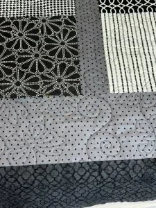 black and gray quilt with silver flowers black and white dots strips and black and white small checker plaid patter.