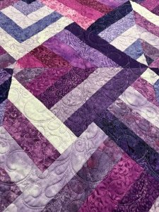 purple snd lavendar shades with deep purples all in strips quilted together 