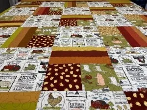 kitchen word quilt top with fruits and vegatable patterns with gold, red, brown retangles and squares.