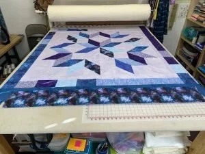 purples, blue, lavendaer, and light purple scrol fabrics with nacy blue border and a solor muticoler outer border. 