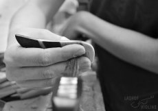 A luthier combs the horsehair on a bass bow while completed a rehair.