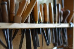A line of chisels and gouges rest in a tool hanger.