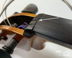 An arrow points to a string groove in the upper nut on a violin. The groove has worn down so far that it is even with the fingerboard.