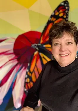 Mary Ellen Winter in front of the Monarch Legit Kits quilt