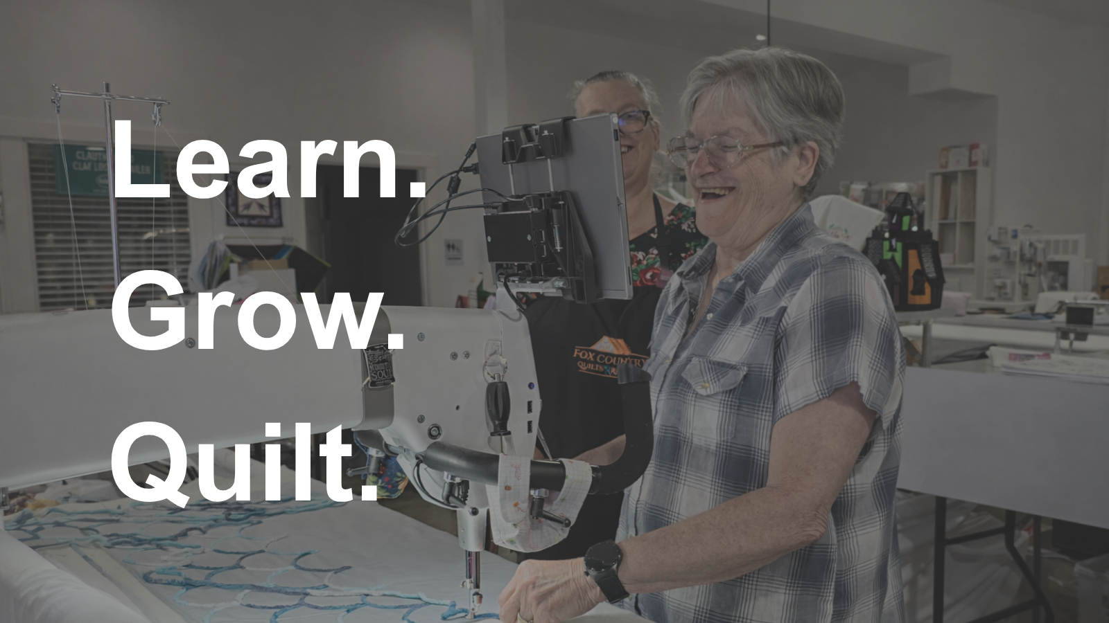 Instructor guiding a student on a longarm quilting machine during a hands-on quilting retreat training in Texas